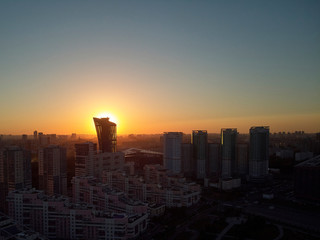 Fototapeta premium Sun is setting behind tower. Evening cityscape. Aerial view