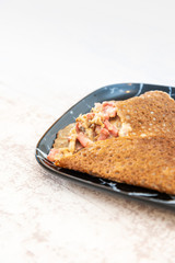 Black wheat and wheat galette topped with cooked ham and emmental cheese