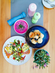 Two delicious poached eggs with salmon on toast served with mixed vegetables and lettuce in white ceramic plate