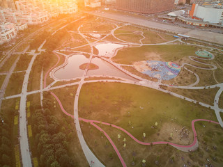 Newly built city park with playgrounds and ponds in the evening sun rays. Aerial view