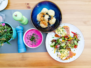 Two delicious poached eggs with salmon on toast served with mixed vegetables and lettuce in white ceramic plate