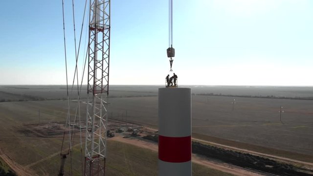 Building process of wind energy power tower mill, under construction. Assembling tower, column, pillar. Green, clean, renewable energy. Aerial footage.