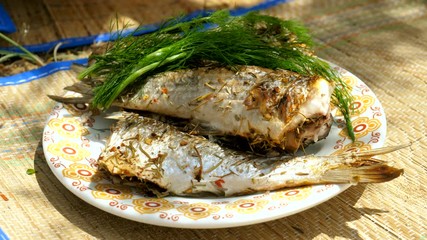 Mackerel, perch, sea bass, dorado, mullet, tuna. Close-up shot of delicious fish grilled on barbecue grill, lying on the plate. 4K
