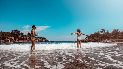 Mother and daughter standing on the beach and enjoying