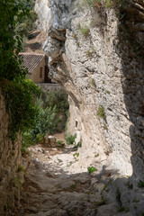 alley street cut into the rock of the mountain with houses in hilltop village Oppede Le Vieux in...