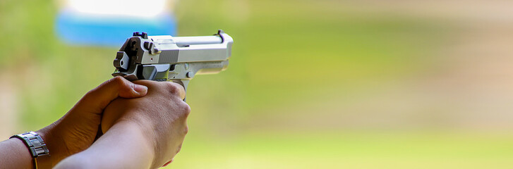 Banner size,The hand is firing a gun in the shooting range