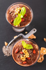 Healthy food concept Chia seeds, chocolate milk pudding with goji and dried walnuts in small Glass on black slate board background