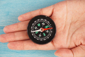 hands holding a magnifying glass on the compass. Selective focus