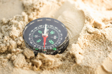 Fototapeta na wymiar A compass on a beach sand. Selective focus to the compass