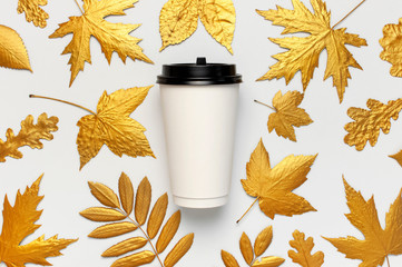 Coffee or tea paper cup, golden autumn leaves on light gray background top view flat lay. Take away coffee cup, mockup. Coffee love, layout for design. Fall concept. Autumn background. Copy space