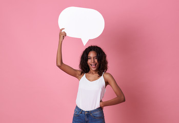 Smiling happy african woman holding blank speech bubble and looking at the camera on pink  background.