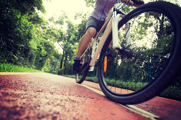 Woman cyclist riding a bike on sunny park trail in summer