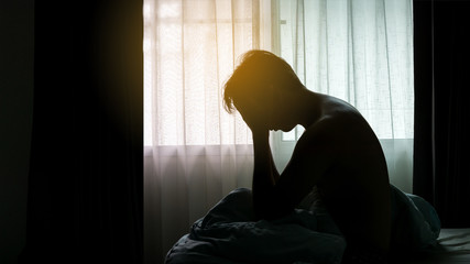 Depressed Man sitting head in hands on the bed in the dark bedroom , Stress, depression, Bipolar...