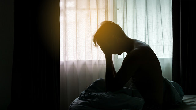 Depressed Man sitting head in hands on the bed in the dark bedroom , Stress, depression, Bipolar disorder,  concept