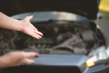 Woman is showing on her broken car.
