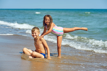 Cheerful children relax on the sea coast . Children's summer vacation