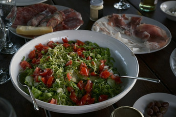 Mediterranean salad of lettuce, tomatoes and cucumbers on a rustic covered table at an outdoor dinner