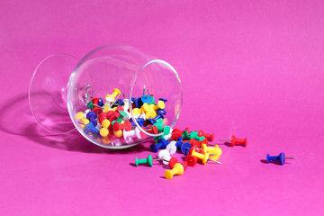 Push pins in a glass on a pink background. Abstraction
