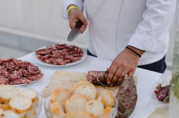 Italian cook cutting a salami