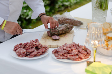 Italian cook cutting a salami