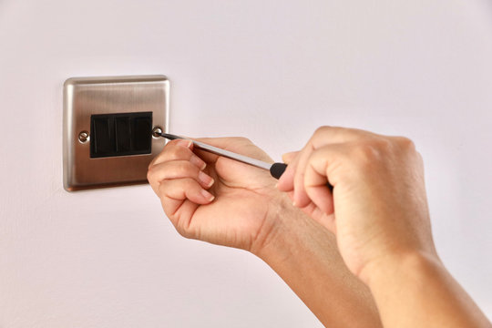 A female electrician fitting a light switch