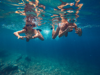Underwater photo of mother and daughter snorkeling in the sea