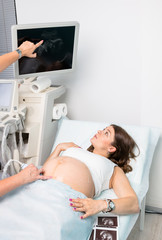 Doctor showing sonogram on monitor during obstetric ultrasonography