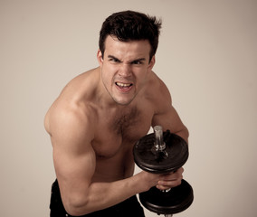 young muscular man lifting weights over dark background