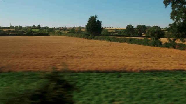 Passenger view of amazing croplands and rolling hills in the Cotswolds in England, UK, an Area of Outstanding Natural Beauty with 787 square miles, the second largest protected landscape in England