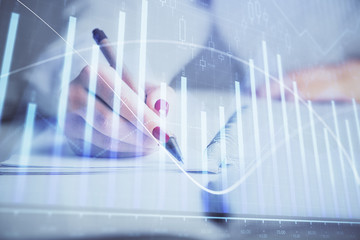 Double exposure of woman's hands making notes with forex graph hologram. Concept stock market analysis.