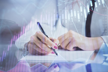 Double exposure of hands making notes with forex chart huds. Stock market concept.