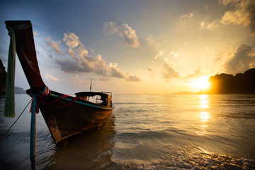 Amazing sunset with longtail boats silhouette at Railay beach, Thailand.