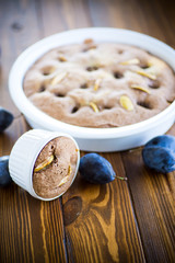 sweet cooked sponge cake with plums, on a table.