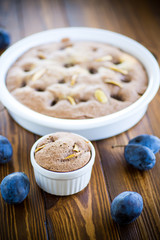 sweet cooked sponge cake with plums, on a table.