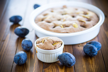 sweet cooked sponge cake with plums, on a table.