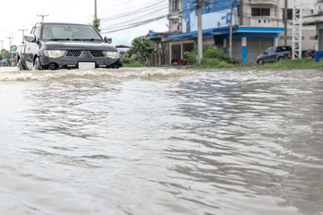 Cars driving on a flooded road, The broken car is parked in a flooded road. .