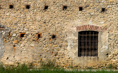 Fototapeta na wymiar Old window with bars in stone wall