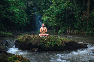 Yoga practice and meditation in nature. Man practicing near river