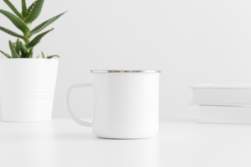 Enamel mug mockup with a aloe vera in a pot and books on a white table.