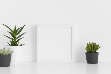 White square frame mockup with a various types of succulent plants on a white table.