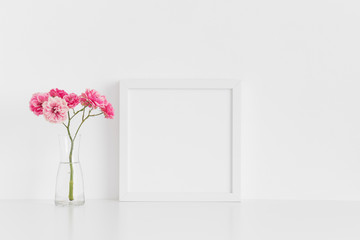 White square frame mockup with pink roses in a glass vase on a white table.