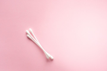 Cotton buds for cleaning ears on a pink background lie diagonally.