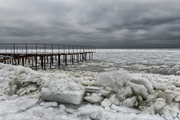 Harsh winter view of the Black Sea coast. Odessa. Huge ice floes and pier in outgrowths of ice and...