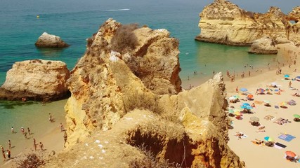 Establishing aerial wide view of pristine waters and beautiful rock formations in Tres Irmaos Beach in Alvor, The Algarve, Portugal