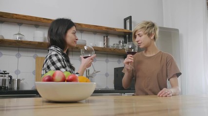 Lesbians drinking wine in kitchen