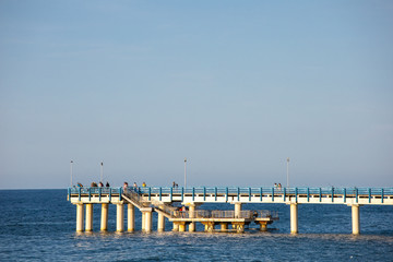 Fototapeta na wymiar tourists walk on the pier near the sea