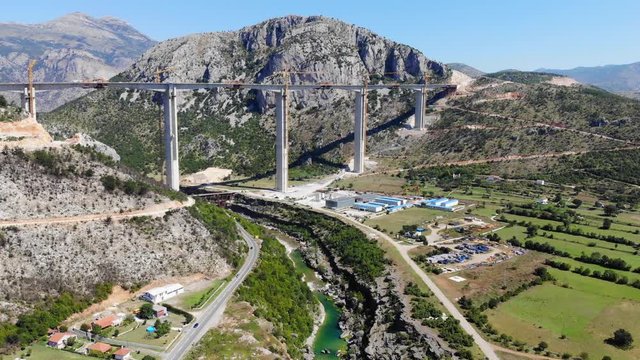 Aerial view construction of bridge of a new highway through the Moraca canyon in Montenegro. Drone shot architectural wonder of the highest bridges within the region, height pillars of 160 meters