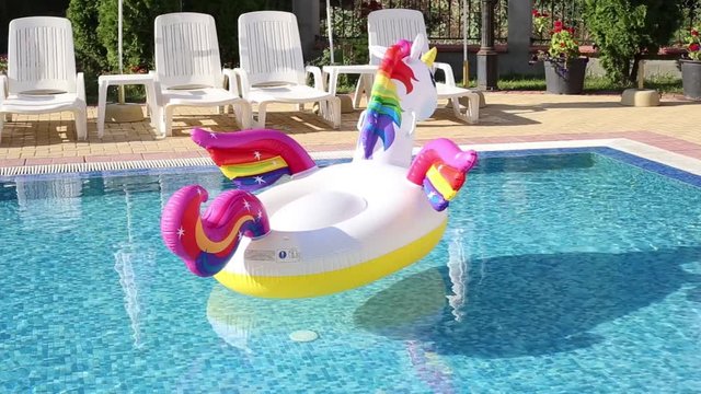 Inflatable unicorn in pool. Pool party, summer holidays, beach vacation. Fantasy swim ring for summer pool trip.