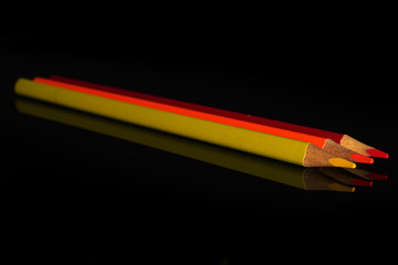 Group of three whole colored pencil isolated on black glass