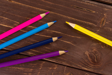 Group of five whole colored pencil flatlay on brown wood